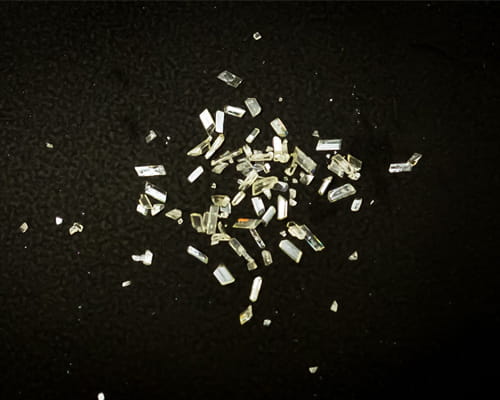A scatter of clear, rectangular and irregularly shaped crystals on a black background.