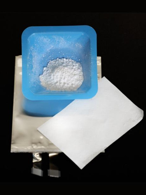 A blue container with white powder on top of a white napkin.