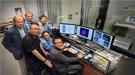 Brookhaven Lab scientists Radoslav Adzic, Vyacheslov Volcov, Lijun Wu (back), Wei An, Jia Wang, and Dong Su (front) gathered in the control room for a scanning transmission electron microscope (STEM) in the Center for Functional Nanomaterials.