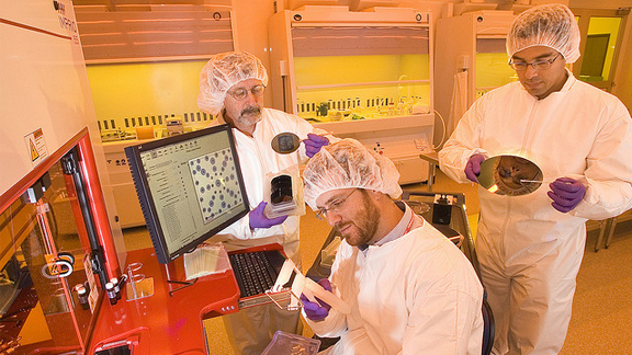 Three scientists infront of a computer station.