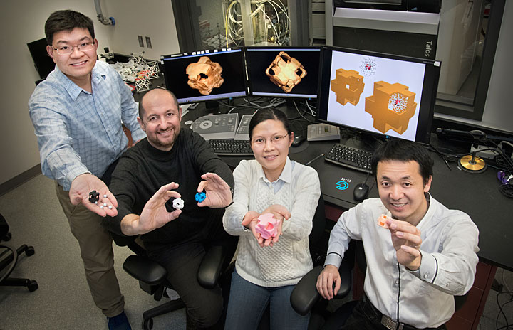 Yugang Zhang, Oleg Gang, Fang Lu, and Mingzhao Liu hold structural models of "nanowrappers" made of gold and silver and featuring holes in the corners. The scientists synthesized these hollow, porous nanostructures through a chemical reaction and characterized them using electron microscopy and optical spectroscopy capabilities at Brookhaven Lab's Center for Functional Nanomaterials.