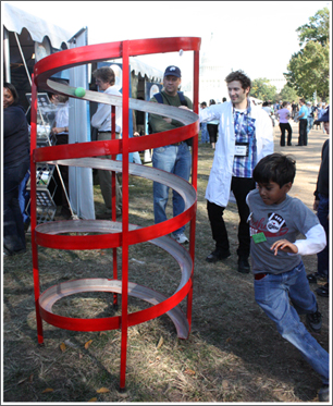 A child races around the accelerator, attempting to beat the ball which is accelerating down the track.