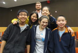 A group of 5 students and their coach pose for the camera