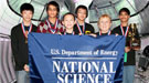 Five students and a teacher wearing medals and holding a banner that reads US Dept of Energy National Science Bowl