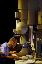 A scientist looking into a large microscope