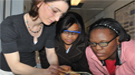 Scientist working in the lab mentoring two interested young students.