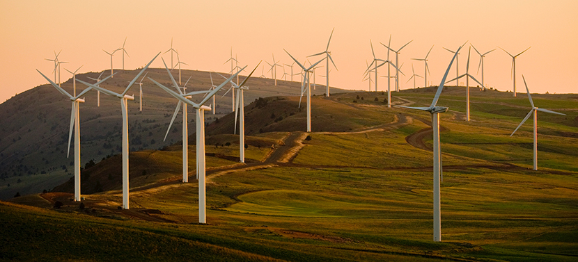 Wind farm on hilly terrain against a setting sun